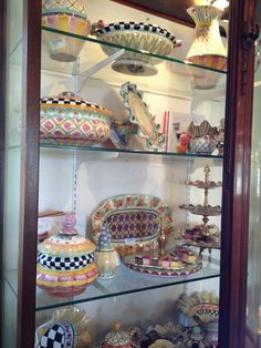 a display case filled with lots of different types of vases and bowls on glass shelves