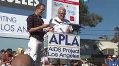 two men are standing at a podium in front of a crowd and one is holding a sign