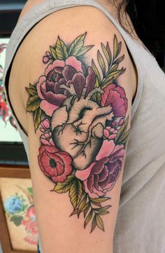 a woman's arm with flowers and a heart tattoo on the left upper arm