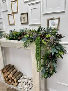 a white fireplace decorated with greenery and pine cones