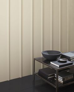 a black bowl sitting on top of a metal table next to a book shelf with books