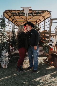 a man and woman standing next to each other in front of a christmas tree stand