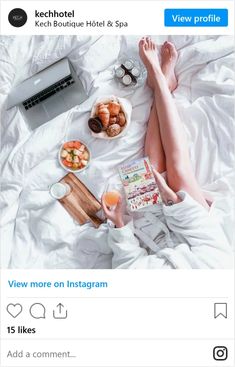 a person laying in bed with food and drinks