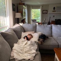 a little boy laying on top of a couch next to a dog sleeping on it