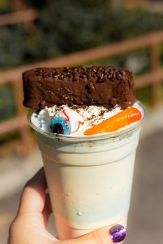 a person holding up a cup with ice cream and chocolate