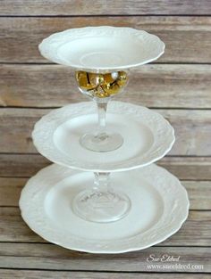 three white plates stacked on top of each other with two glasses filled with gold liquid