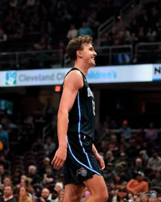 a male basketball player in a black uniform is standing on the court and looking to his left