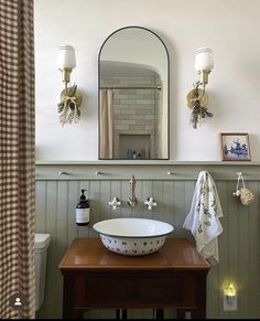 a bathroom sink sitting under a mirror next to a wooden table with a towel on it