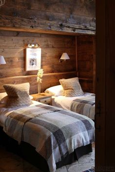 two beds in a room with wooden walls