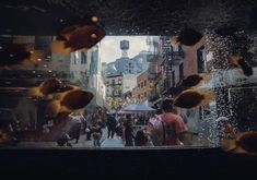 fish swimming in the water near people walking on a city street with buildings behind them