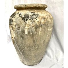 an old vase is sitting on a white sheeted surface with the paint chipped off