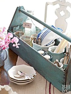 a wooden box filled with dishes and utensils sitting on top of a table