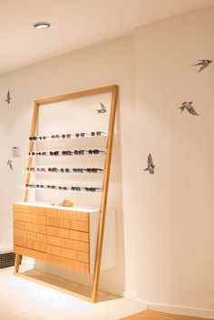 an eyeglass display in the corner of a room with birds on the wall behind it