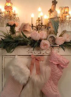 christmas stockings hanging from a mantel with candles in the background and angel figurines