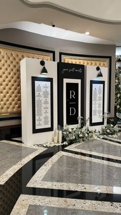 three black and white framed pictures on display in front of a marble floor with flowers