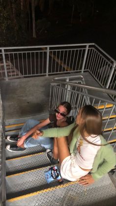 two people sitting on some stairs at night