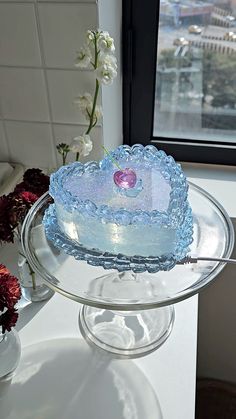 a heart shaped cake sitting on top of a glass platter next to a window