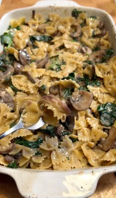 a casserole dish with mushrooms, spinach and cheese in it on a wooden table