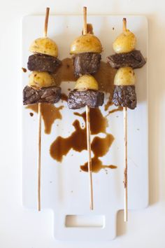 some food is sitting on top of a cutting board with toothpicks sticking out of it