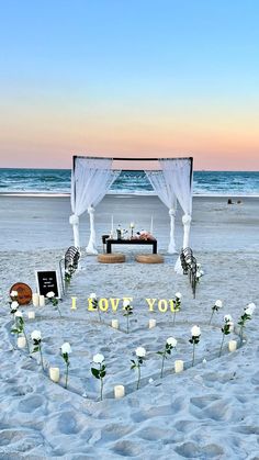 an outdoor wedding setup on the beach with flowers in the foreground and a sign that says i love you