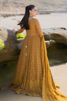 a woman in a yellow dress standing on the beach with her back to the camera