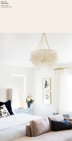 a bedroom with a bed, couch and chandelier hanging from it's ceiling