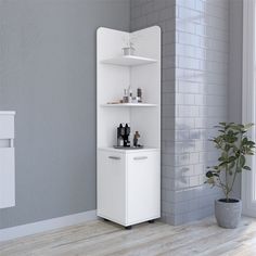 a bathroom with a white cabinet next to a potted plant on the floor in front of a gray brick wall