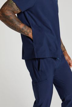 MADE FOR THE WAY YOU MOVE™: The Daniel 2 Pocket Scrub Top gives you the freedom to move. Made from EcoSoftMD™ fabric that breathes and stretches you'll stay cool, calm, and collected even into overtime. Navy Relaxed Fit Athleisure Activewear, Navy Relaxed Fit Activewear For Athleisure, Navy Relaxed Fit Activewear For Sports, Navy Activewear With Pockets For Workout, Navy Cotton Athleisure Activewear, Navy Athleisure Activewear With Pockets, Navy Activewear With Pockets For Gym, Breathable Cotton Activewear For Loungewear, Athleisure Sports Tops With Pockets