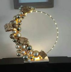 a christmas wreath made out of ornaments on top of a black table next to a framed photo