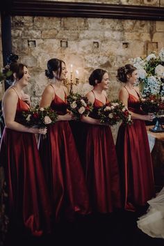 the bridesmaids are all wearing red dresses and holding bouquets in their hands