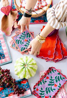 the woman is working on her handmade table cloths with grapes and other decorative items