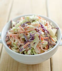 a white bowl filled with coleslaw on top of a wooden table