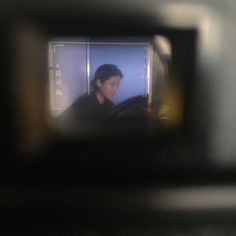 a woman is seen through the reflection of her camera lens in a vehicle's side view mirror