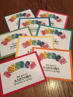 four cards with rainbows on them sitting on a table