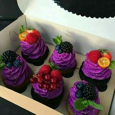 there are many cupcakes with purple frosting and fruit on top