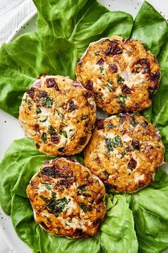 three crab cakes on top of some green leafy leaves next to a cup of coffee