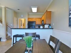 a dining room table with chairs and a plant on top of it in front of an open kitchen