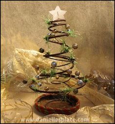 a small christmas tree made out of wire and glass beads is displayed on a table