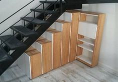 the stairs are built into the wall next to the bookshelf and cupboards