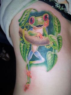 a frog tattoo on the back of a woman's thigh, with leaves around it