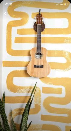 a guitar hanging on the wall next to a plant