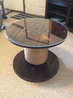 a round glass table sitting on top of a wooden stand in a living room next to a tv