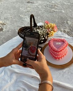 a woman is holding up her cell phone to take a picture of the cake on the table