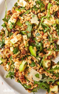 a white plate topped with salad covered in nuts and greens