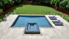 an aerial view of a pool with lounge chairs in the foreground and grass behind it