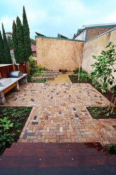 a brick patio with benches and trees in the background