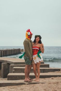 a man and woman in costumes standing on the beach next to some steps looking at the ocean