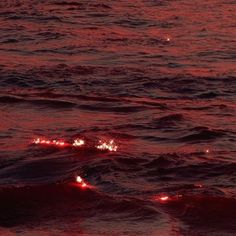 the sun is setting over the ocean with red light coming from the water's surface