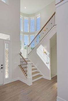 an empty room with white walls and wood floors, stairs leading up to the second floor