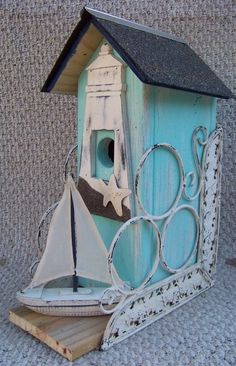 a blue birdhouse with a sailboat on it